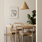 The Risu Dining Chair by Ethnicraft in a dining room with a wooden table and pendant light.