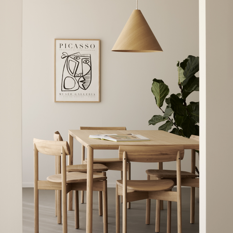 The Risu Dining Chair by Ethnicraft in a dining room with a wooden table and pendant light.