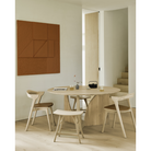 The oak Round Geometric Dining Table from Ethnicraft in a living space with upholstered Bok Dining Chair and Osso Dining Stool.