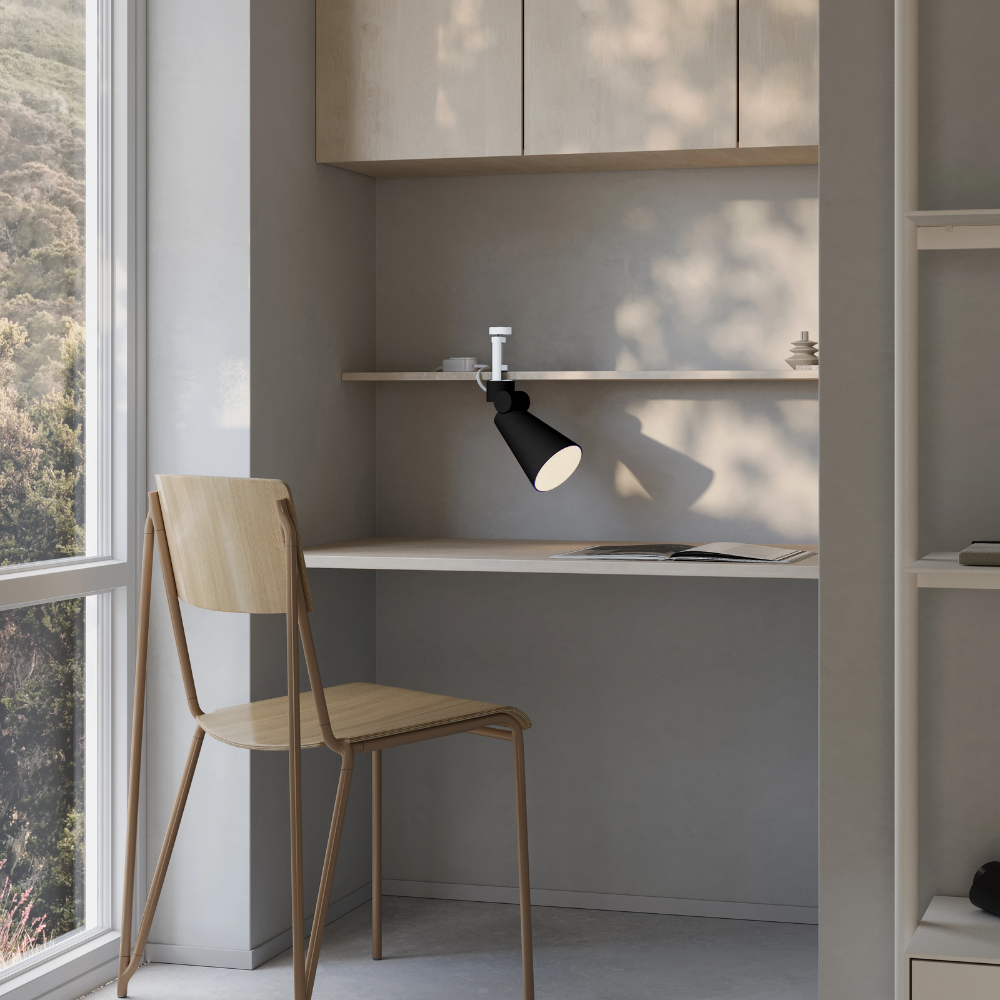 The carbon Aim Clamp Light from Gantri with the white clamp in a living room.
