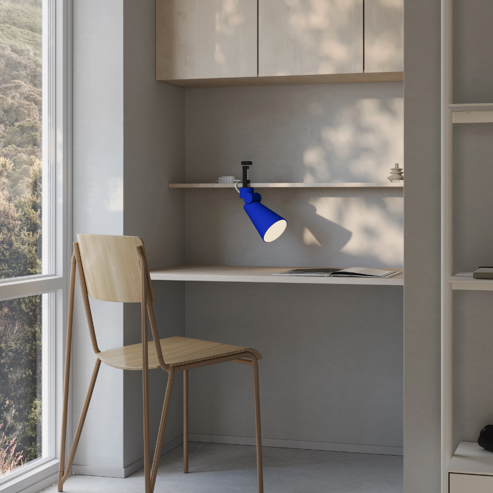The cobalt Aim Clamp Light from Gantri with the black clamp in a home office.