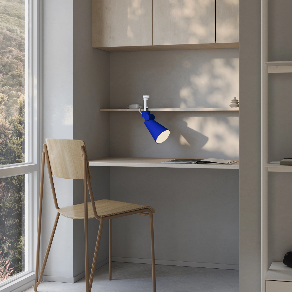 The cobalt Aim Clamp Light from Gantri with the white clamp in a living room.