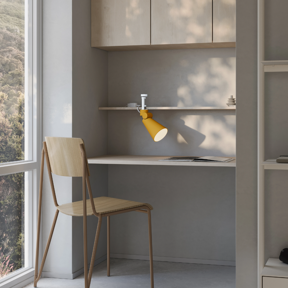 The mustard Aim Clamp Light from Gantri with the white clamp in a living room.