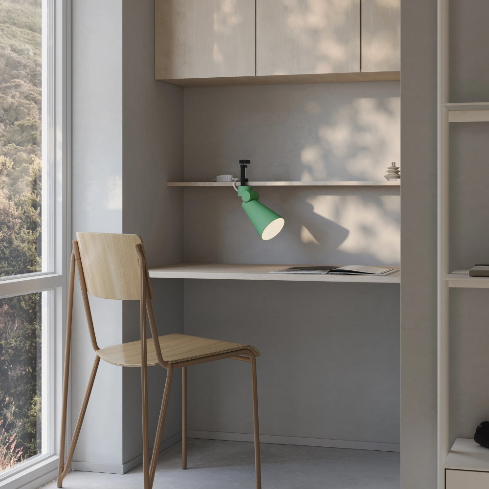 The sage Aim Clamp Light from Gantri with the black clamp in a home office.