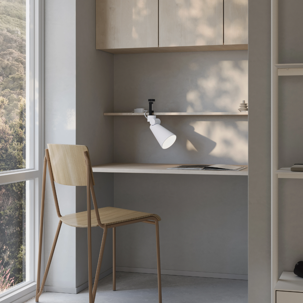 The snow Aim Clamp Light from Gantri with the black clamp in a home office.