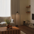 The walnut Aim Floor Light from Gantri with the white rod option in a living room next to a couch.