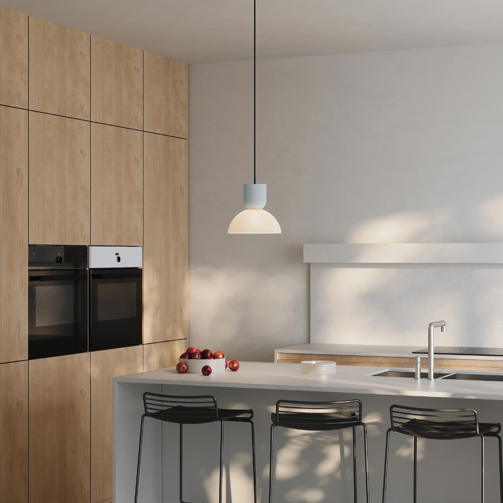 The mist Buia Pendant Light from Gantri with the black cord in a dining and kitchen area above a kitchen bar.