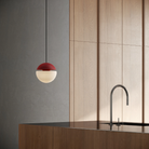 The canyon Cora Pendant Light from Gantri with the black cord in a kitchen and dining area above an island with a sink.