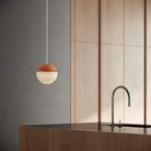 The persimmon Cora Pendant Light from Gantri with the white cord in a living room.