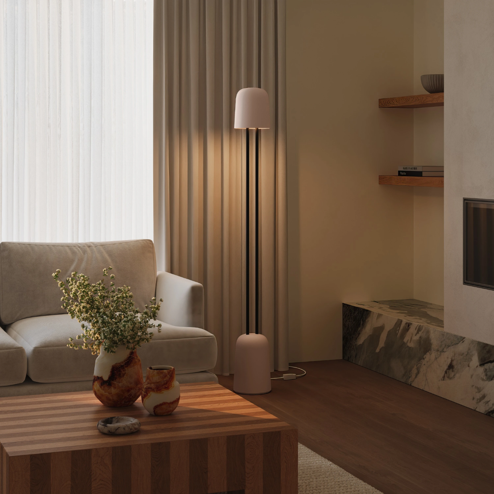 The coral Gio Floor Light from Gantri with the black rod option in a living room near a couch.