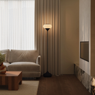 The carbon Kobble Floor Light from Gantri with the black rod option in a living room beside a couch.