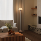 The coral Kobble Floor Light from Gantri with the white rod option in a lounge space next to a sofa.