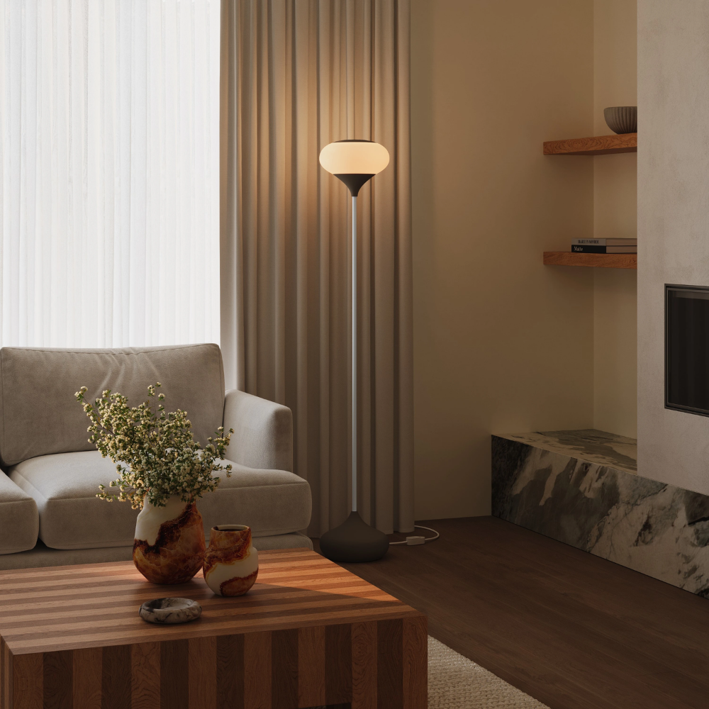 The walnut Kobble Floor Light from Gantri with the white rod option in a lounge space next to a sofa.