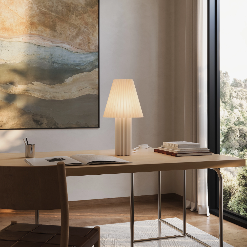 The Pleat Table Light from Gantri in a business space beside several books.