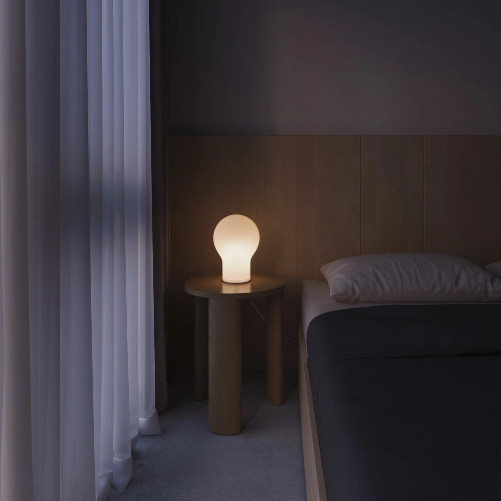 The Squish Table Light from Gantri lit, lighting up a guest bedroom.
