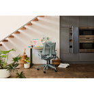 The glacier Cosm Office Chair from Herman Miller in a living room near a kitchen.