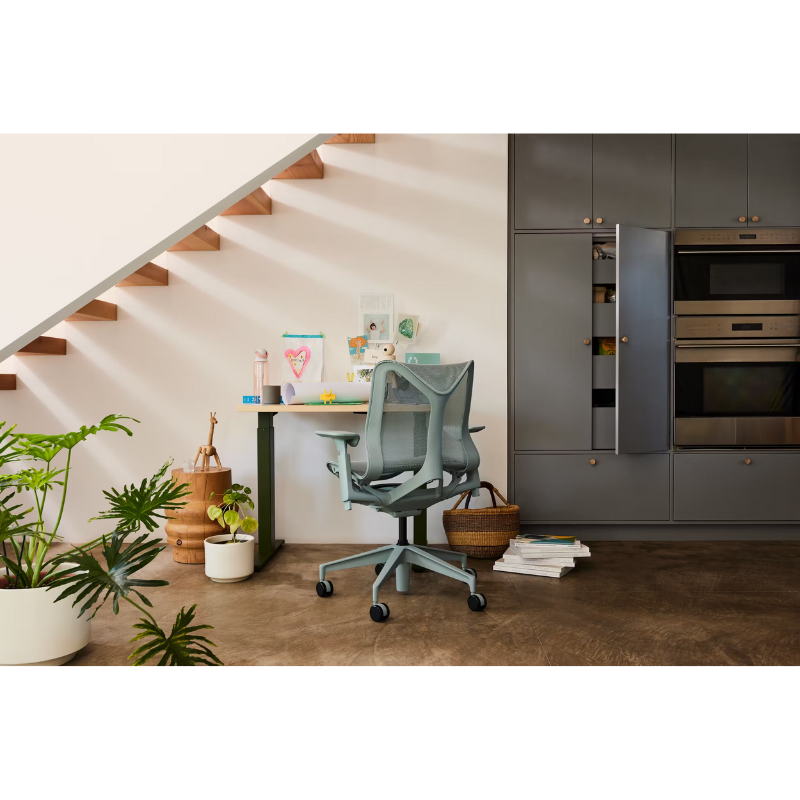 The glacier Cosm Office Chair from Herman Miller in a living room near a kitchen.