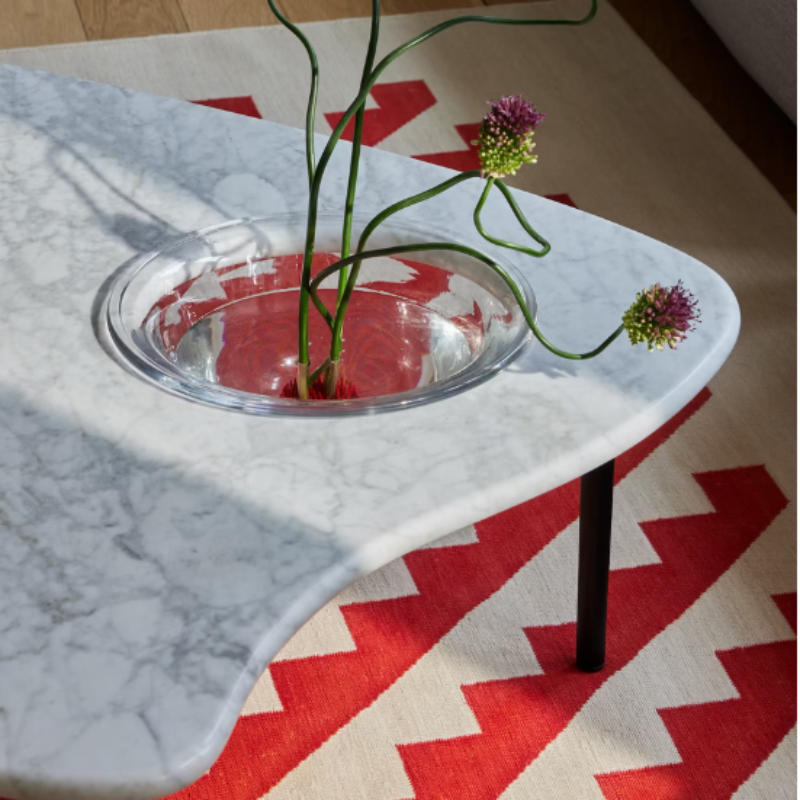 The low carrara marble Cyclade Table from Herman Miller with the cast-glass bowl storing a plant.