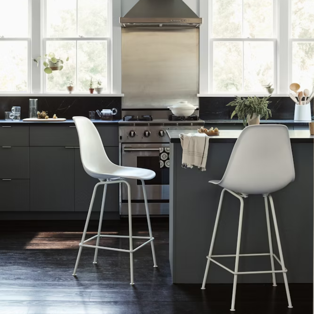 The white shell Eames Molded Plastic Bar Height Stool from Herman Miller in a living room.