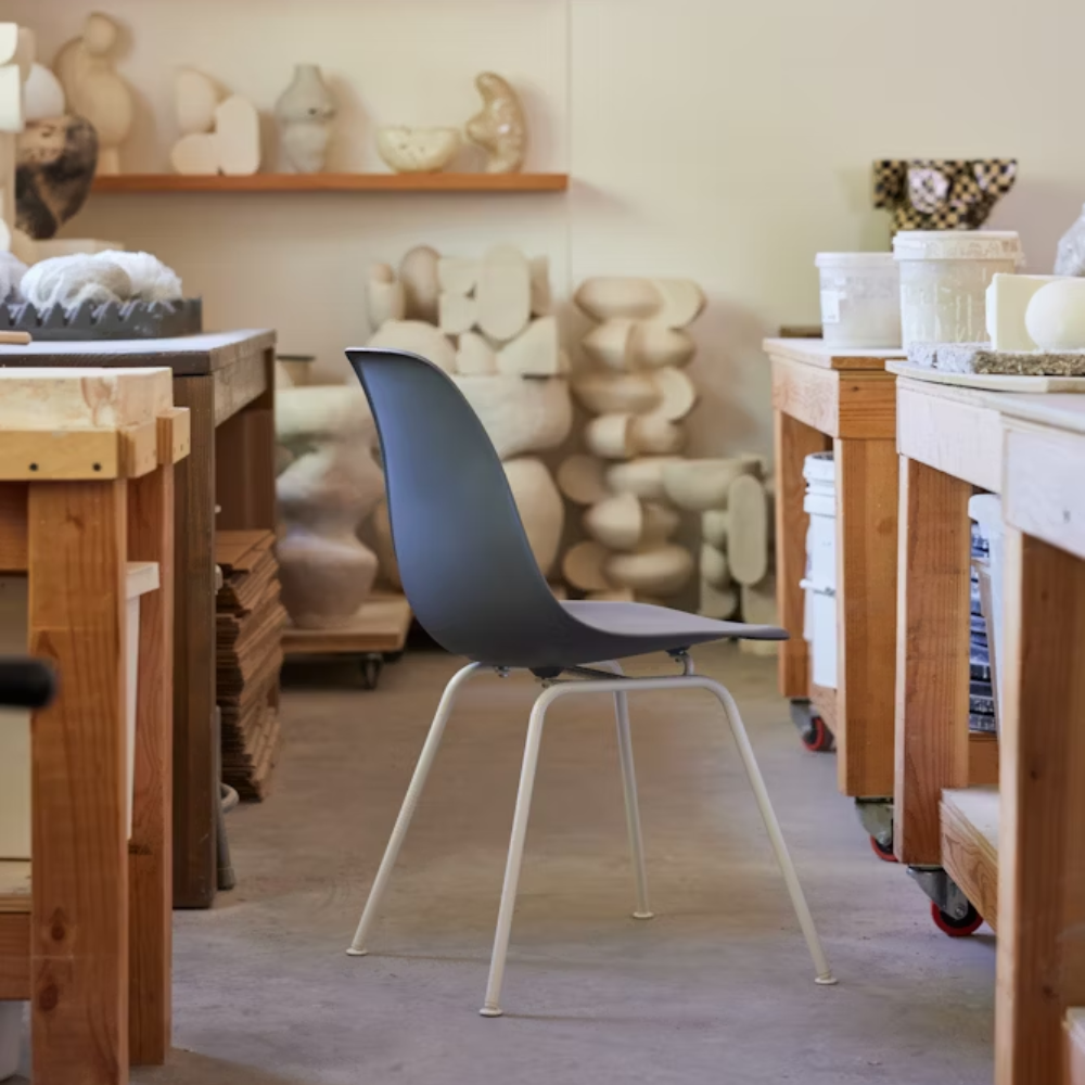 The medium gray shell Eames Molded Plastic Side Chair 4-Leg Base from Herman Miller in a living room.