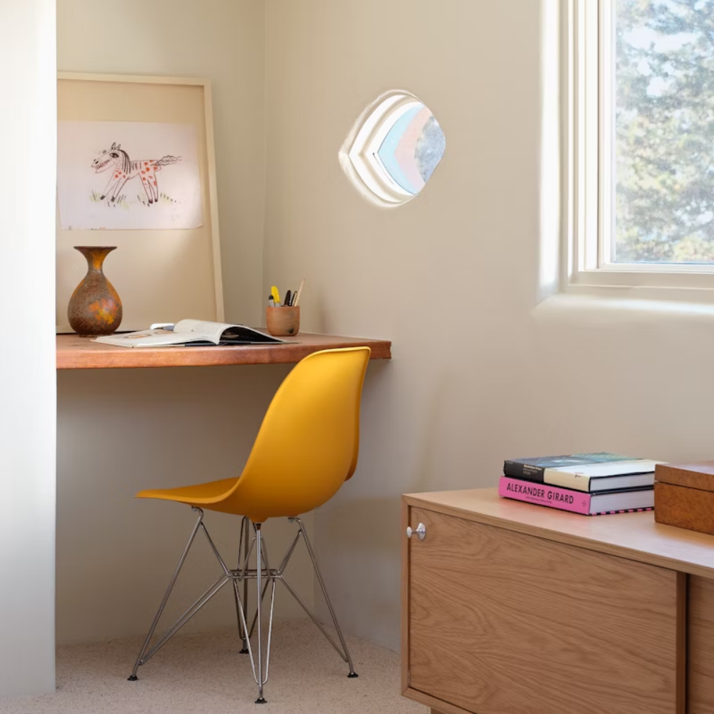 The deep yellow shell Eames Molded Plastic Side Chair Wire Base from Herman Miller in a home office.