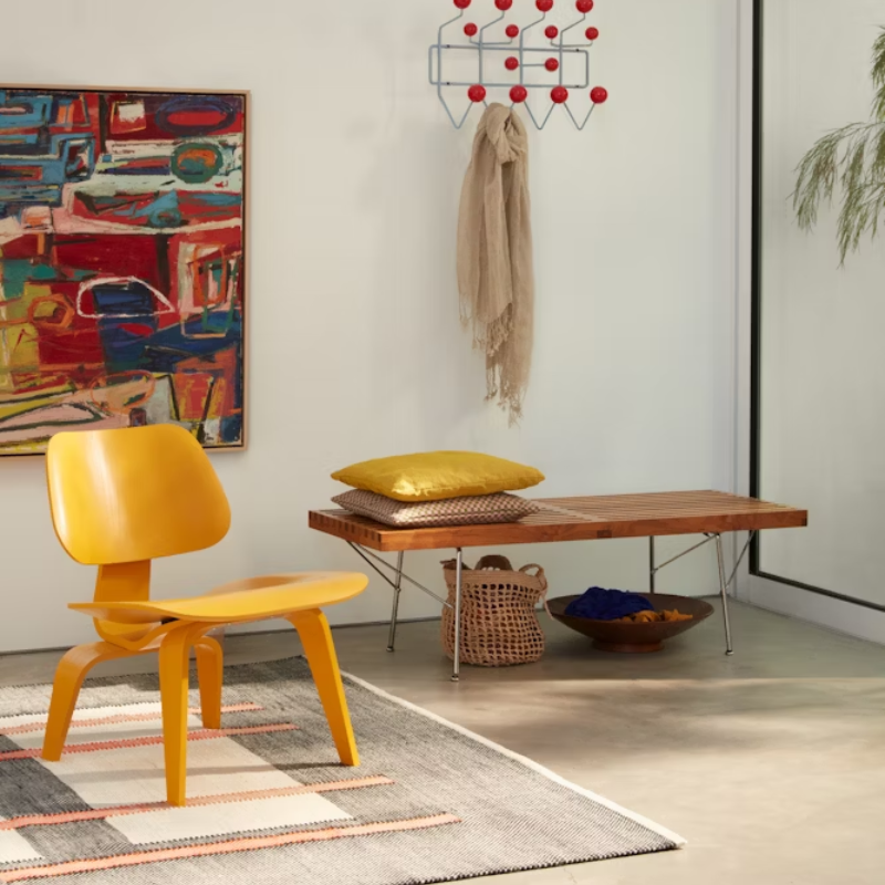 The Deep Yellow Stain Eames Molded Plywood Lounge Chair Wood Base from Herman Miller in an entryway.