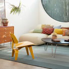 The Deep Yellow Stain Eames Molded Plywood Lounge Chair Wood Base from Herman Miller in a living area.
