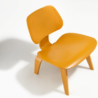 The Deep Yellow Stain Eames Molded Plywood Lounge Chair Wood Base from Herman Miller in a studio.