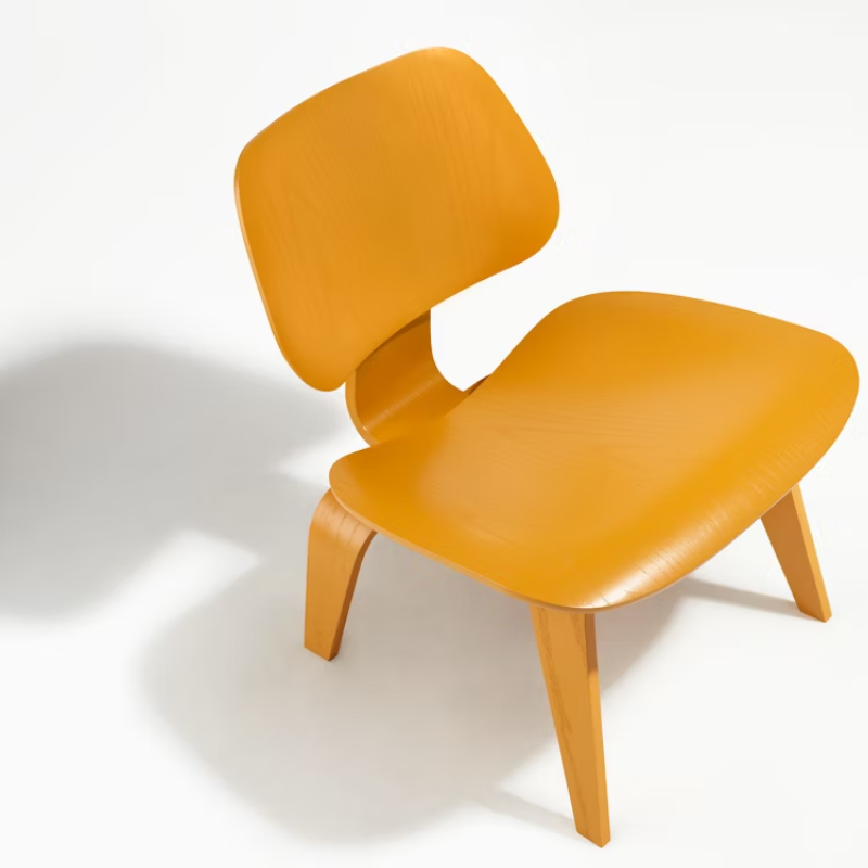 The Deep Yellow Stain Eames Molded Plywood Lounge Chair Wood Base from Herman Miller in a studio.