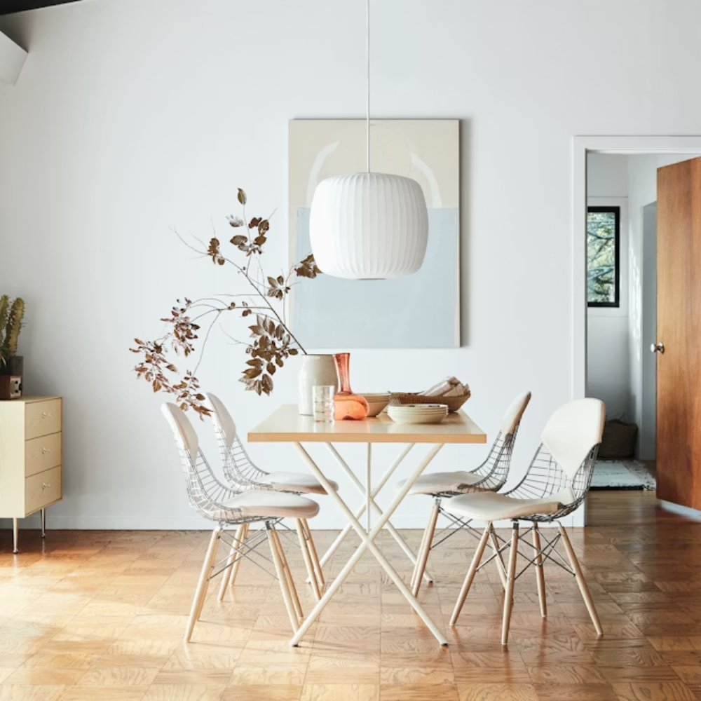 The white ash and white Nelson X-Leg Table from Herman Miller in a dining space.