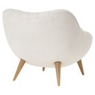 The Rohde Easy Chair from Herman Miller with the warm white whim upholstery and oak leg finish from the back at an angle.