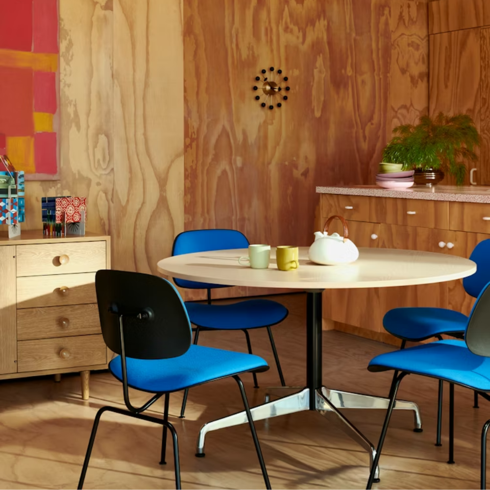 The Upholstered Eames Molded Plastic Dining Chair from Herman Miller with cobalt blue hopsak upholstery, black shell and ultra black leg finish in a dining area.