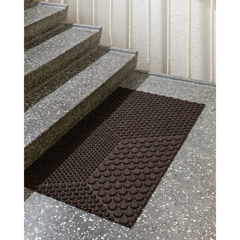 The Hex Doormat by Heymat at the base of a staircase.