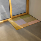 The Mix Teklan Entry Mat from Heymat in medium size next to a sliding door.
