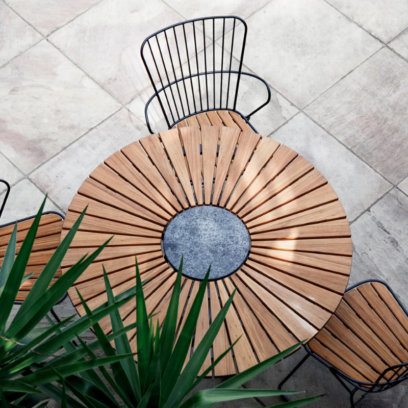 The Circle Outdoor Dining Table by Houe with chairs on a tiled patio showing the top view.
