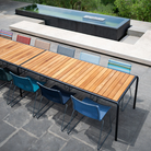 The Click Outdoor Dining Chair No Armrest by Houe in an outdoor dining setup with a wooden table and colorful chairs on a patio.
