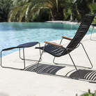 The Click Outdoor Footrest by Houe with a lounge chair beside the pool with palm trees.