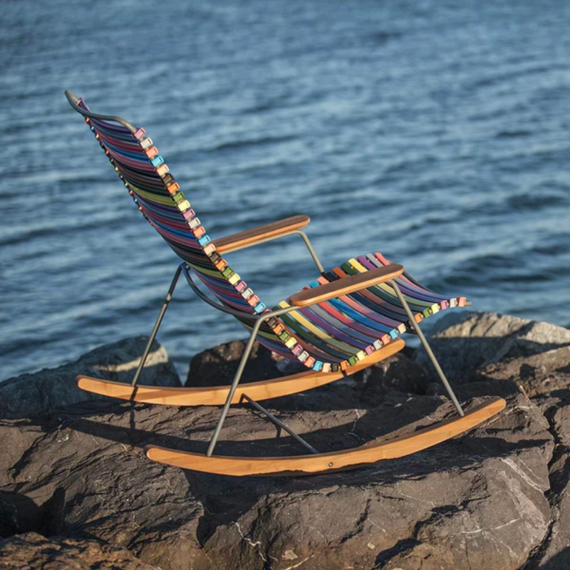 The multicolor Click Outdoor Rocking Chair by Houe on a rock in an outdoor area.