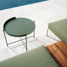 The Edge Tray Coffee Table, Medium in Olive Green beside a pool.