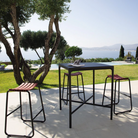 The black Four Outdoor Bar Table Bamboo by Houe with bar chairs in the garden.
