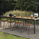 The Four Outdoor Dining Table Bamboo by Houe with metal chairs in a garden setting.