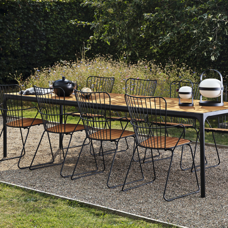 The Four Outdoor Dining Table Bamboo by Houe with metal chairs in a garden setting.