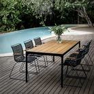 The Four Outdoor Dining Table Bamboo by Houe with chairs by a pool.