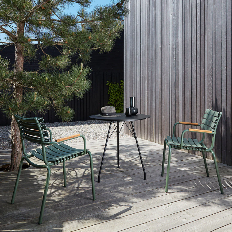 The olive green ReClips Outdoor Dining Chair Bamboo by Houe with a black table on a wooden deck.