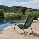 The ReClips Outdoor Rocking Chair by Houe from the poolside with a scenic background.