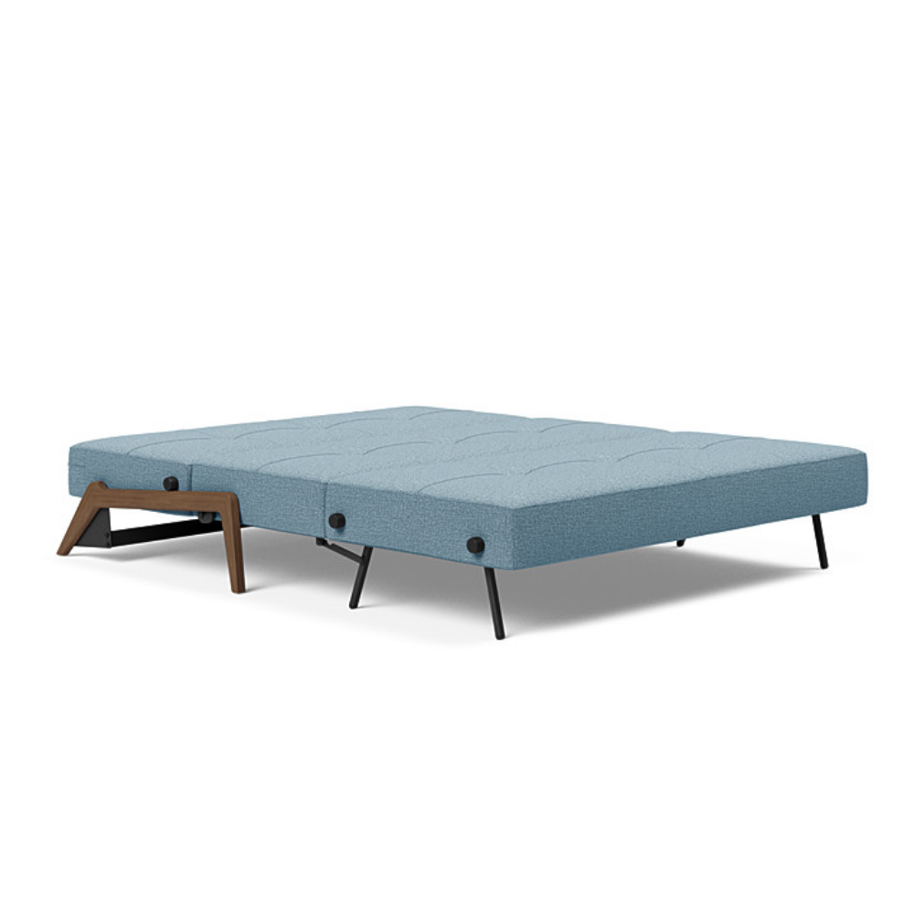 The Cubed Queen Size Sleeper Sofa with Wood Legs from Innovation Living with dark lacquered oak legs and mixed dance light blue 525 upholstery setup as a bed.