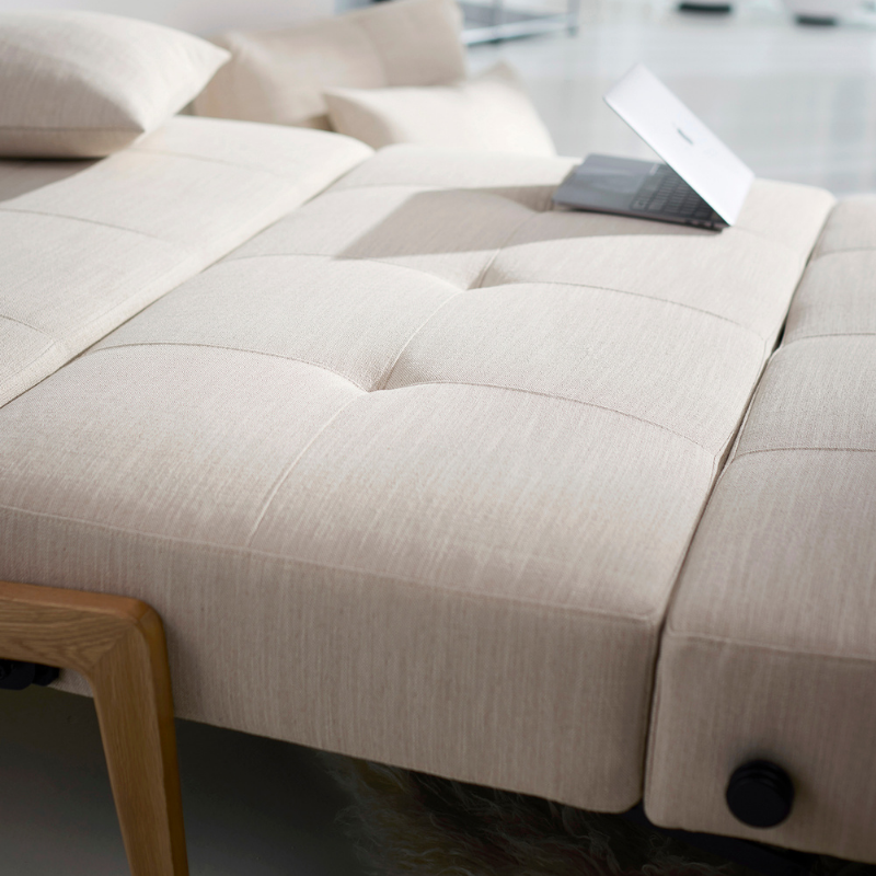 The Cubed Queen Size Sleeper Sofa with Wood Legs from Innovation Living with lacquered oak legs and blida sand grey 612 upholstery in a living room.