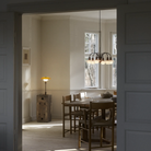 The PH 1/1 Chandelier, 6-Light by Louis Poulsen in a dining room turned on.