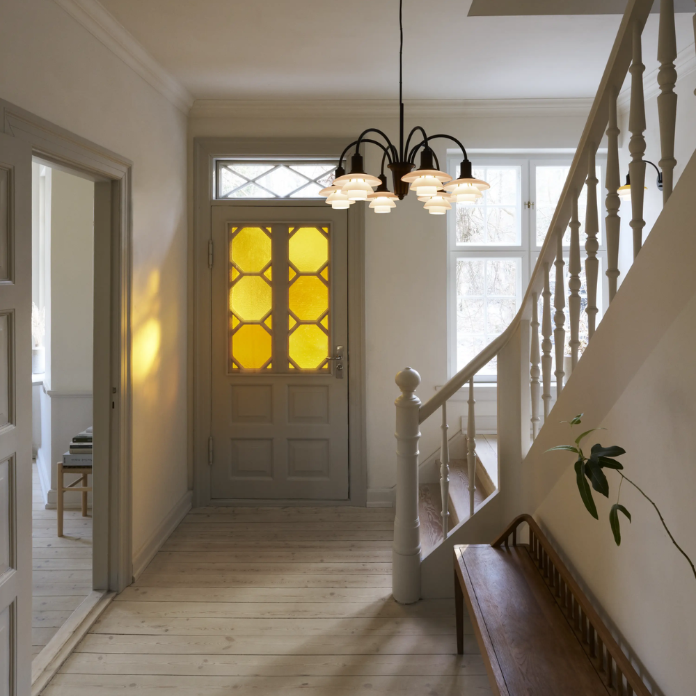 The PH 1/1 Chandelier, 6-Light by Louis Poulsen in an entryway turned on.