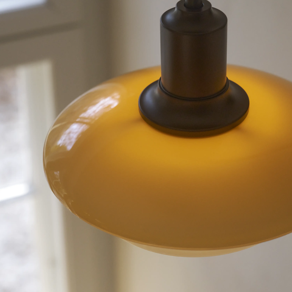 Close up of the top amber shade of the PH 2/2 Wall Lamp Centenary Edition while turned on.